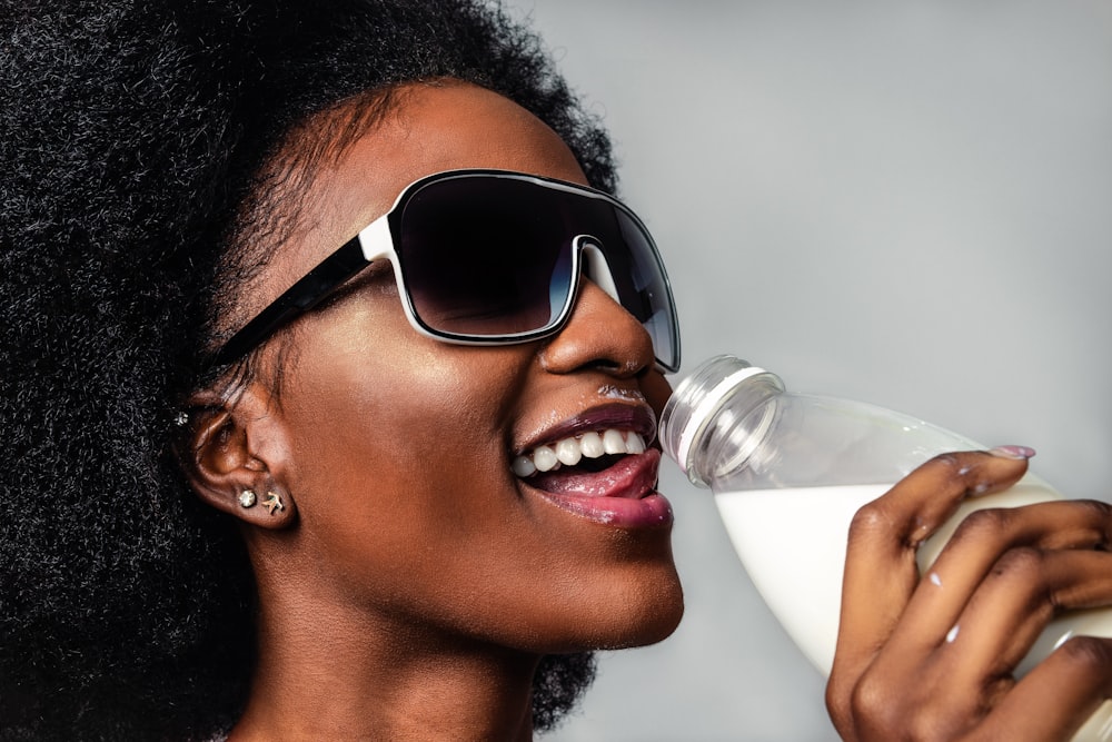 woman wearing black and white sunglasses drinking milk