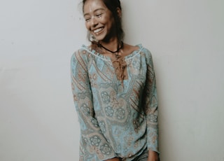 smiling woman wearing blue blouse leaning on wall