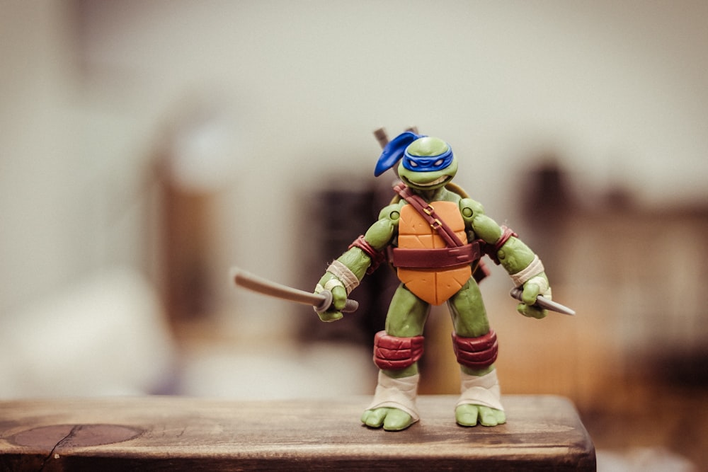 selective focus photography of TMNT Leonardo action figure on brown wooden surface