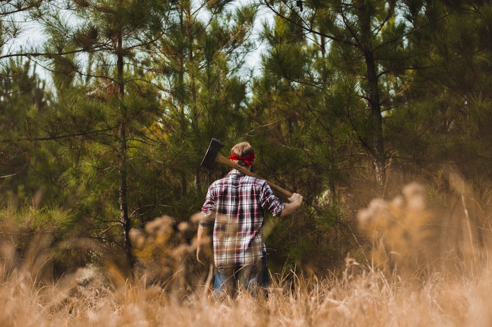 person holding ax watching trees during daytime