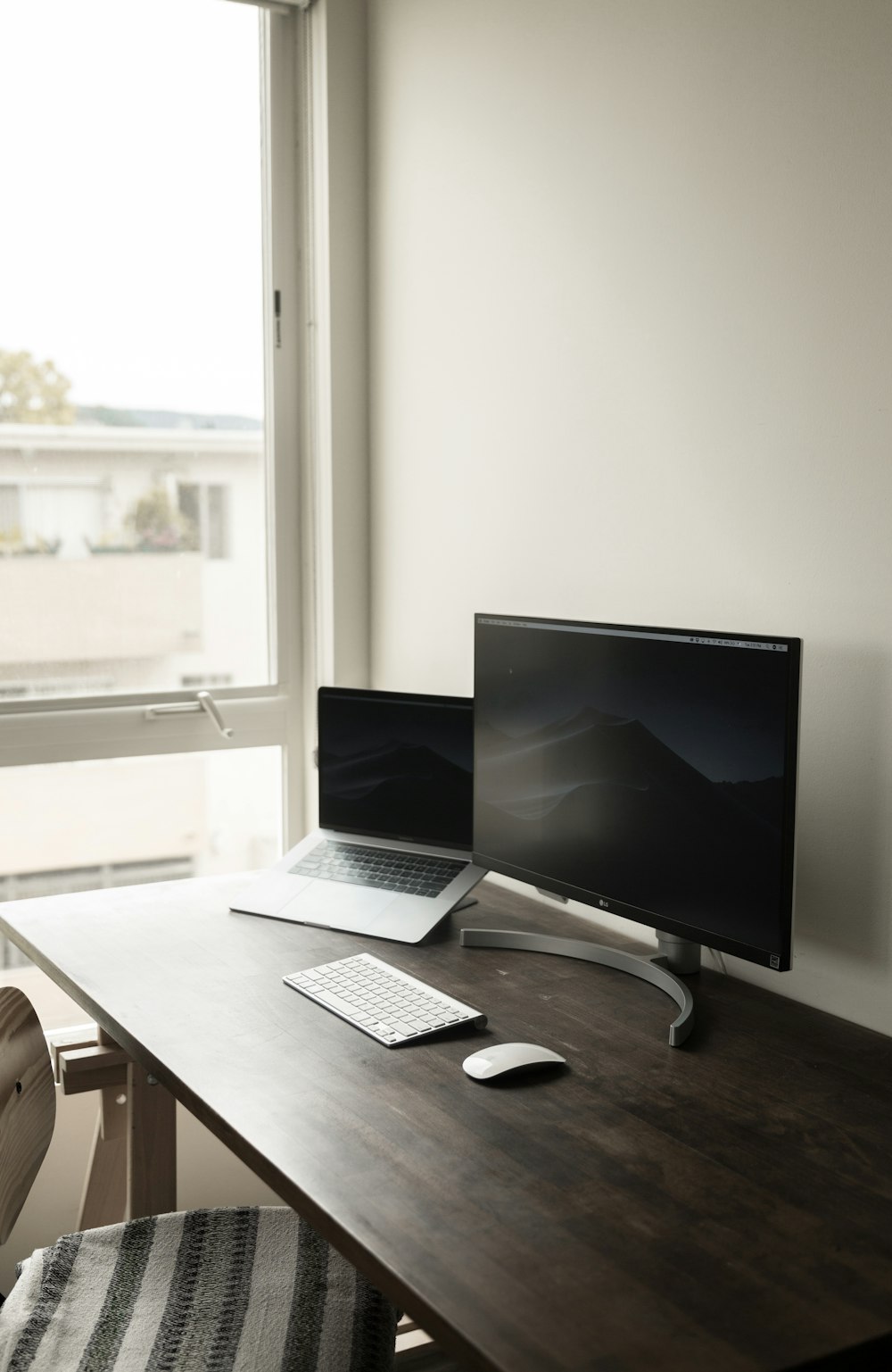 Computermonitor in der Nähe von Laptop Computer auf braunem Holztisch