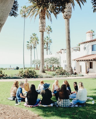 people sitting on ground while forming round during daytime