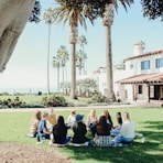 people sitting on ground while forming round during daytime