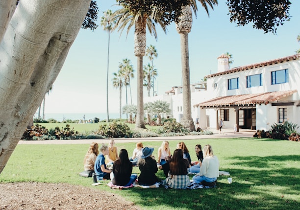 people sitting on ground while forming round during daytime