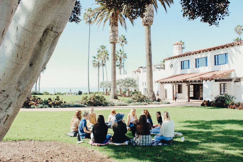 people sitting on ground while forming round during daytime