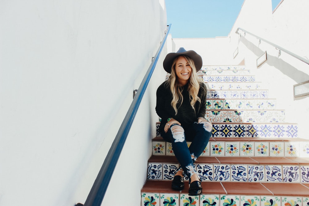 woman in black shirt sitting on stairs during daytime