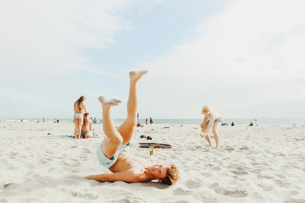 smiling man lying on white sand during daytime