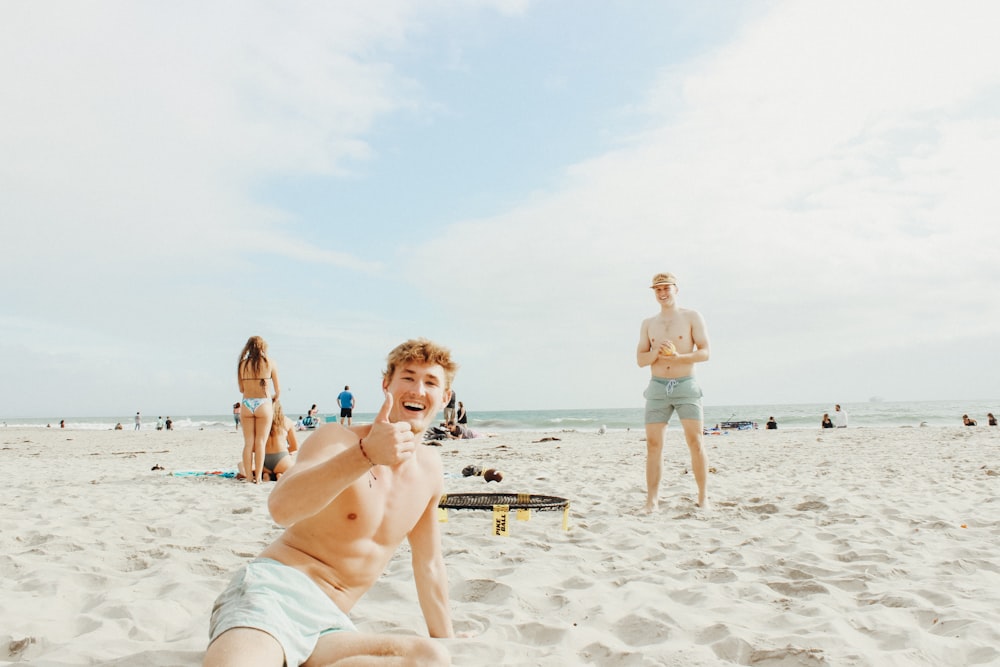 man sitting on sand near sea during daytime