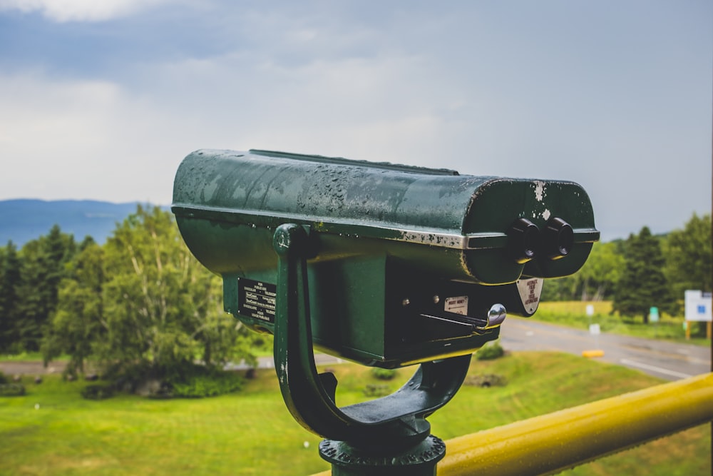 green telescope near yellow metal railing