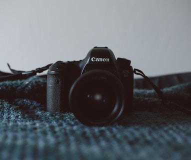 black Canon DSLR camera on black textile