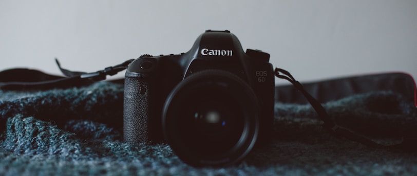black Canon DSLR camera on black textile