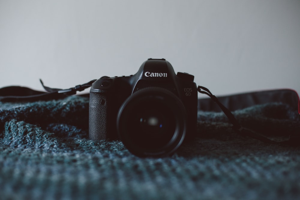 black Canon DSLR camera on black textile
