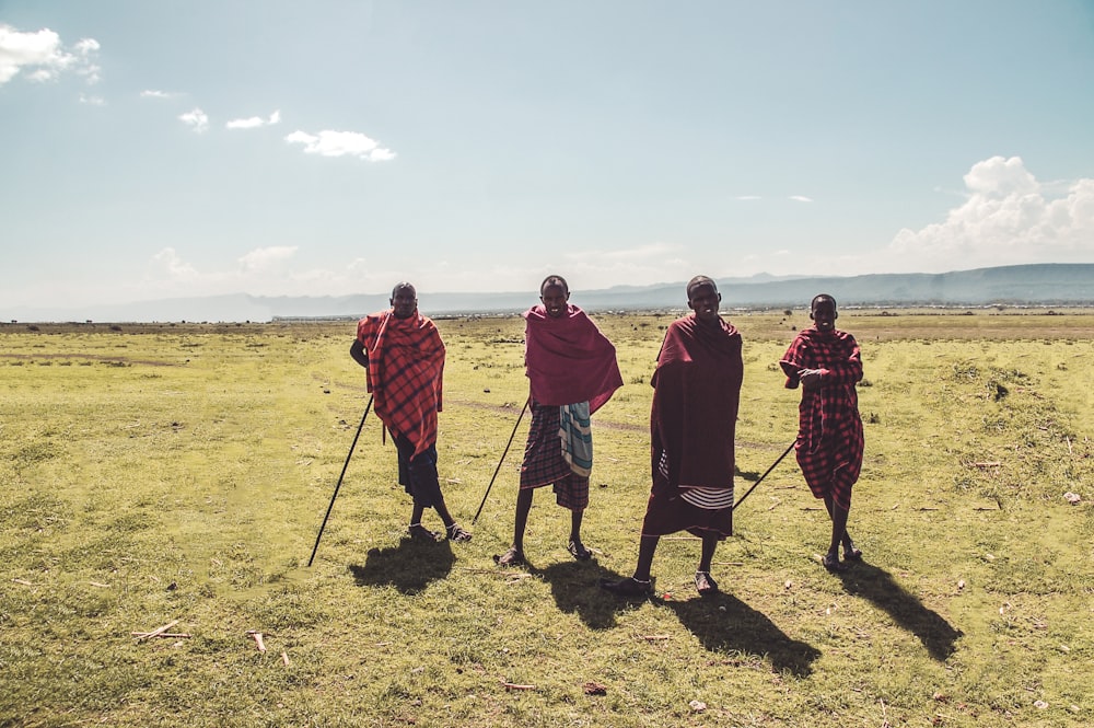 four man standing on green grass during daytime