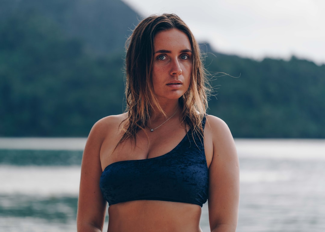 selective focus photography of standing woman wearing gray bra on seashore during daytime