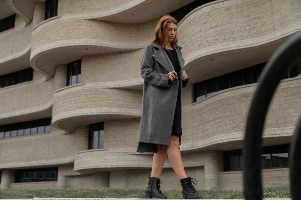 woman wearing coat walking near brown building