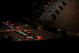 A sleek M-Audio console glowing with neon orange lights in a dark studio.
