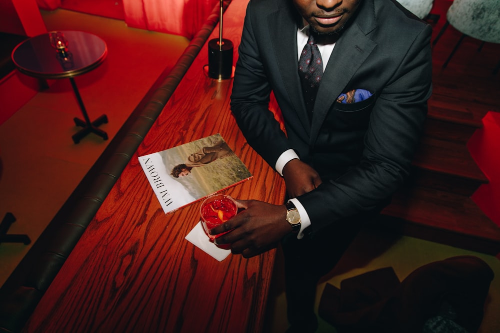 hombre con blazer negro sosteniendo un vaso para beber