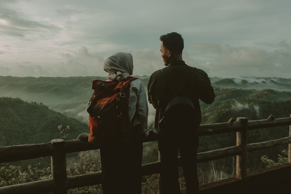 man and woman standing beside fence