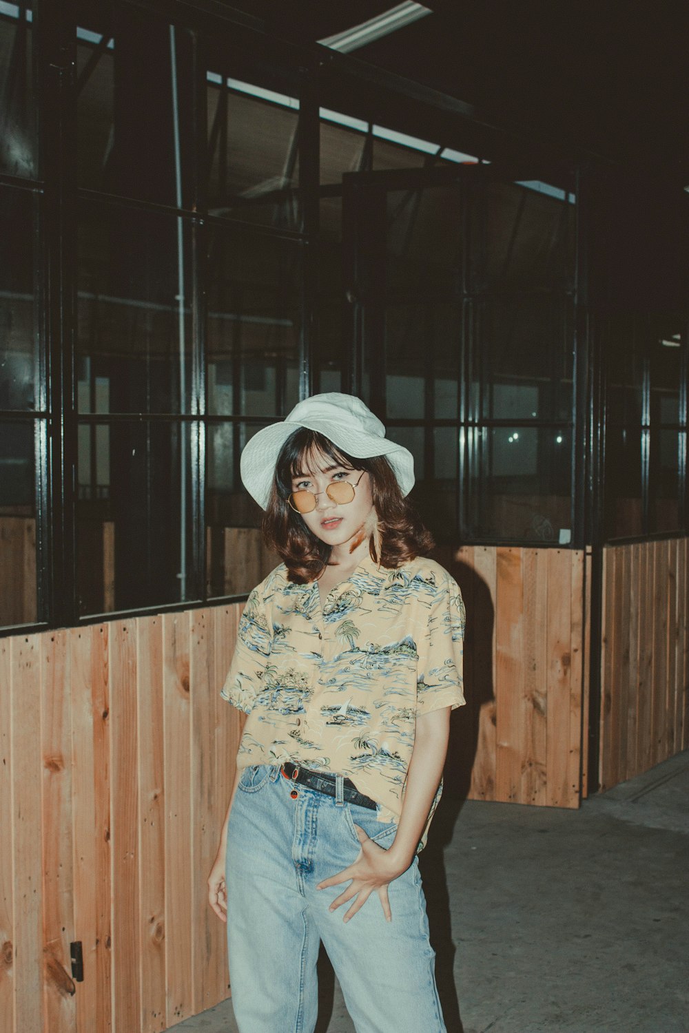 woman wearing green and yellow button-up shirt while standing near glass window