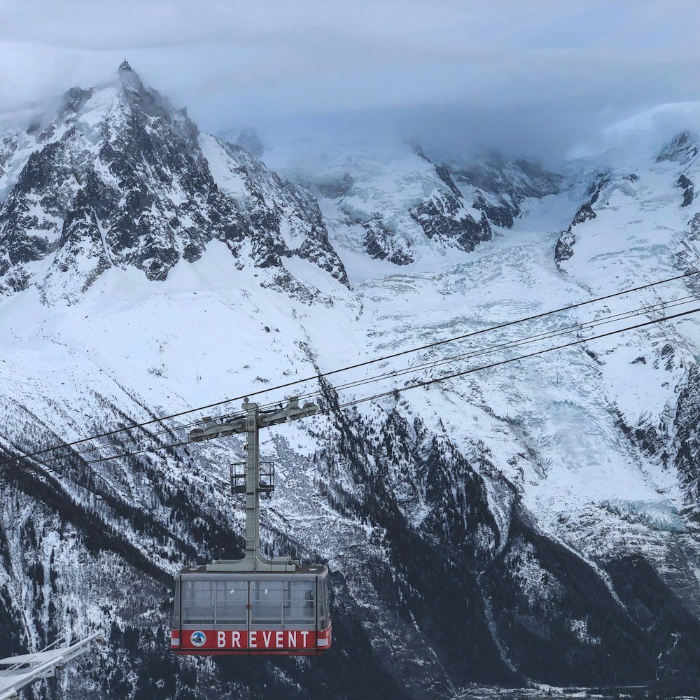 gray and red cable car near mountain covered with snow