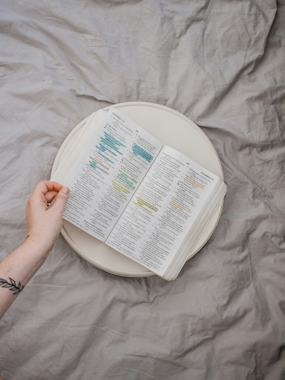 person browsing a book white on white tray