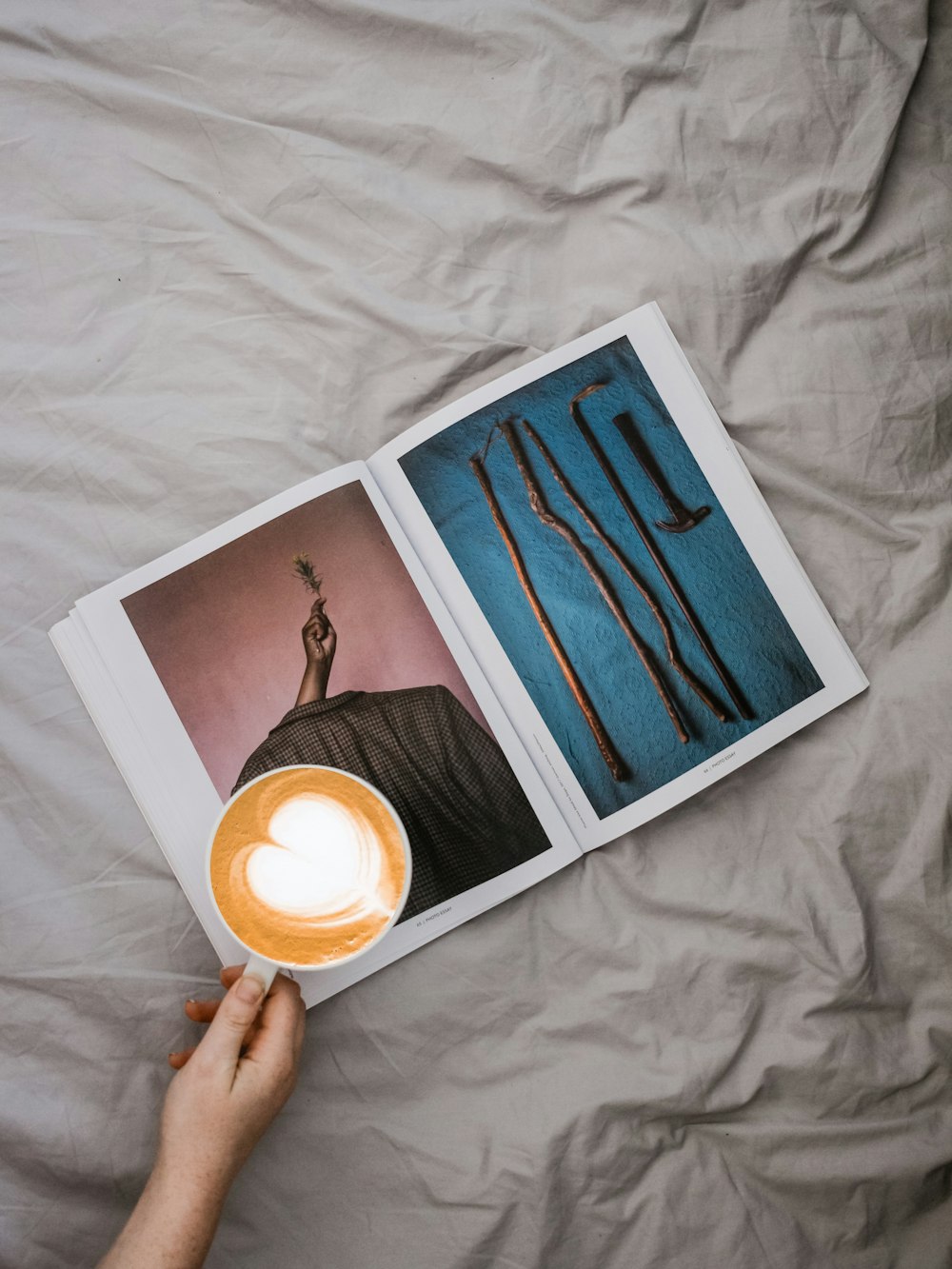 person holding mug of cappuccino on open magazine