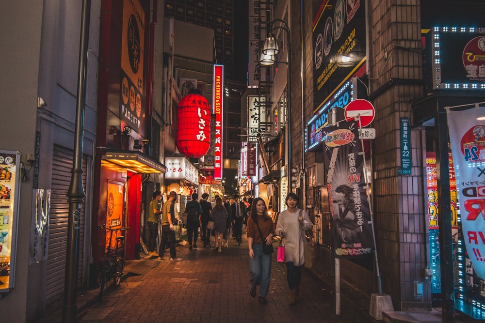 people walking on pathway near buildings at night