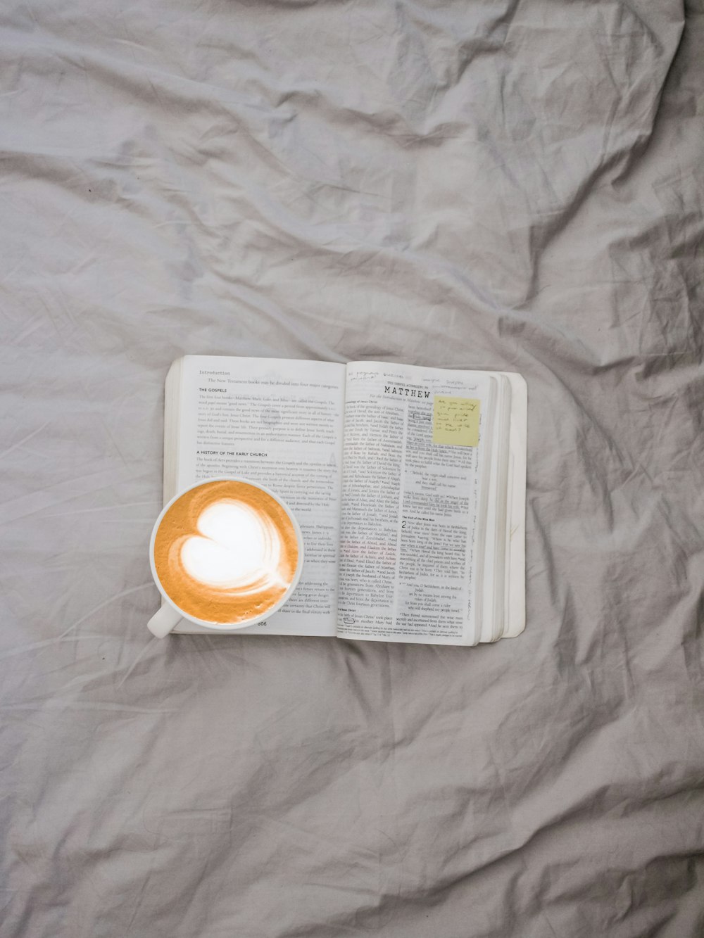 weißer Becher gefüllt mit Kaffee auf dem Buch