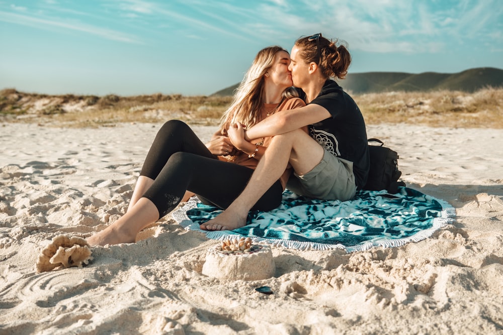 man and woman kissing while sitting on blue mat