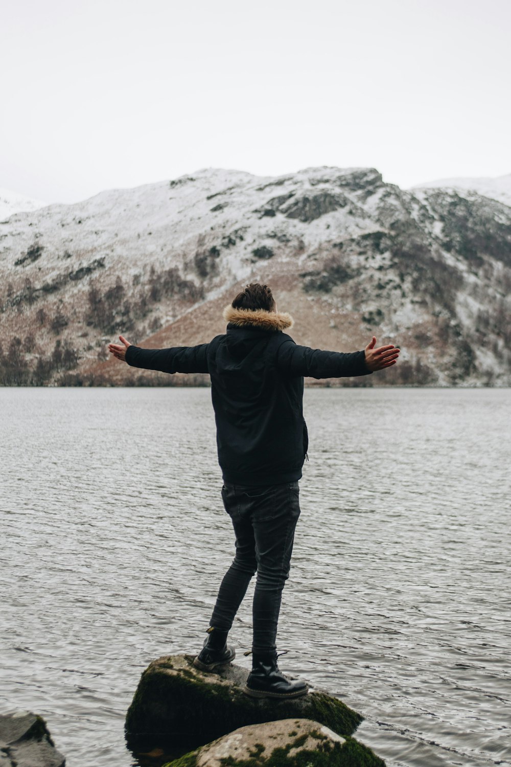 person standing on rock near body of water