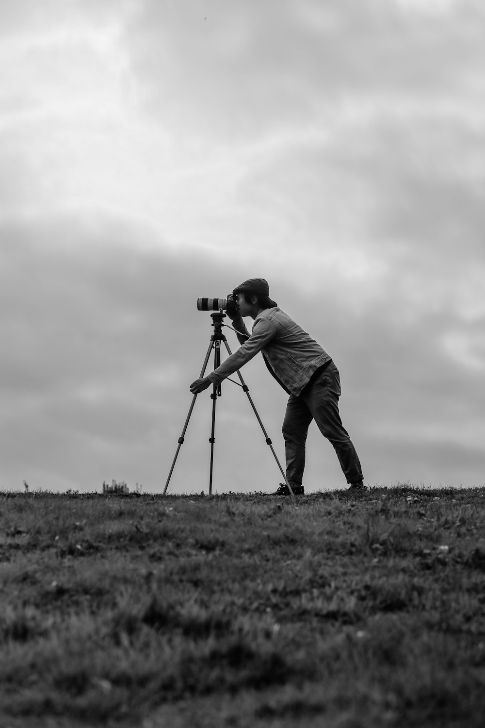 grayscale photo of man standing beside camera