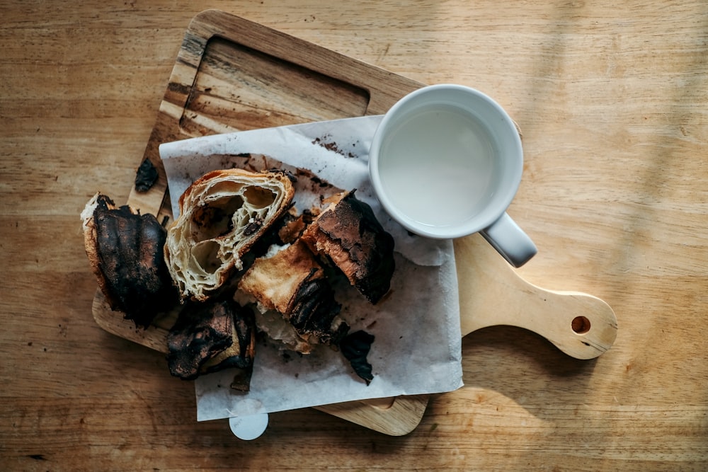 grilled food beside cup of milk on chopping board