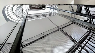 A sleek modern metal spiral staircase photographed from below with natural industrial lighting