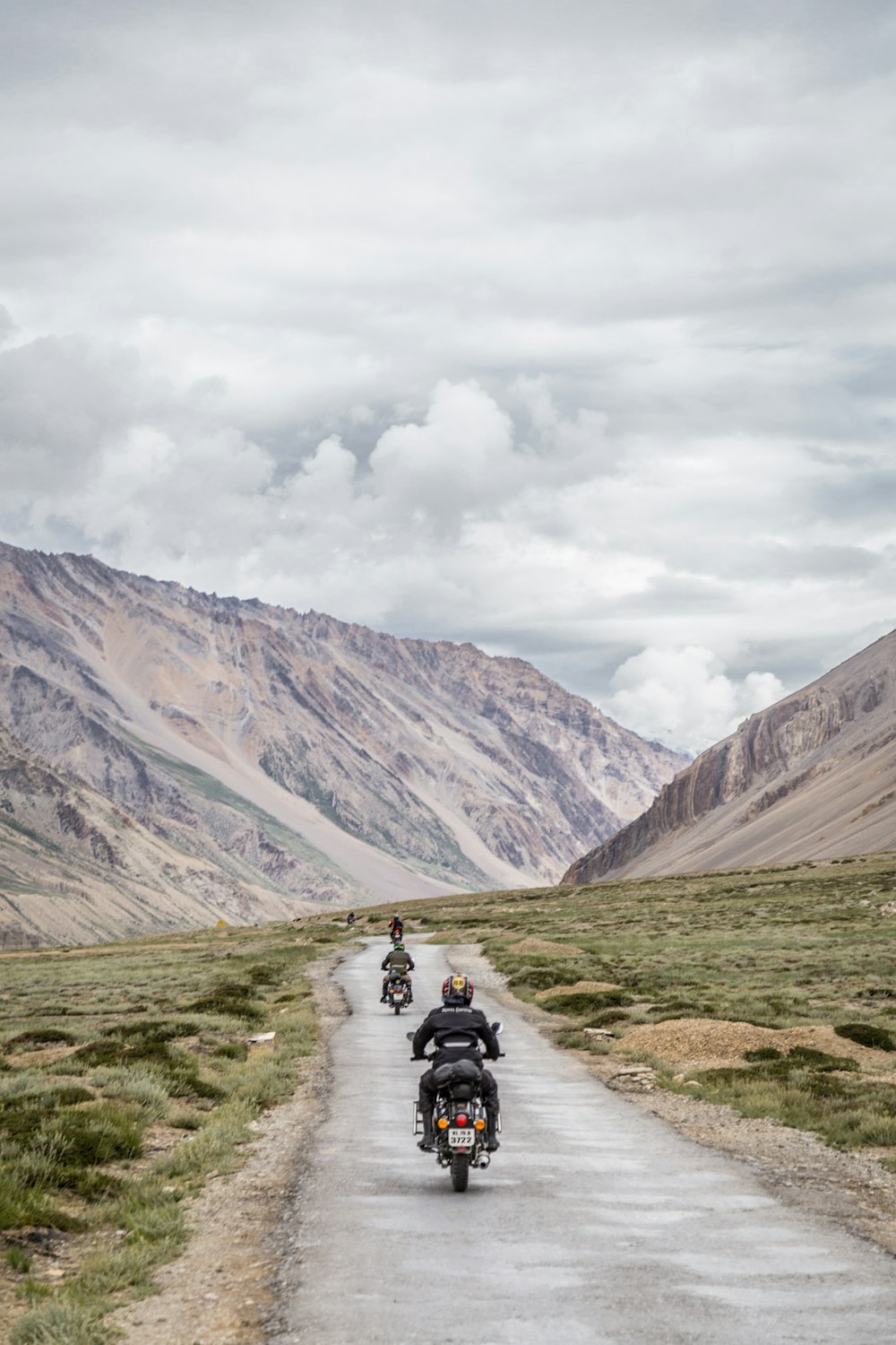 two motorcycles driving on grey road