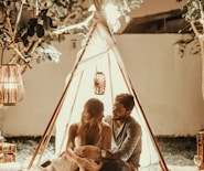 couple sitting inside tepee hut with lights