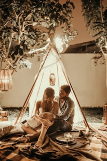 couple sitting inside tepee hut with lights