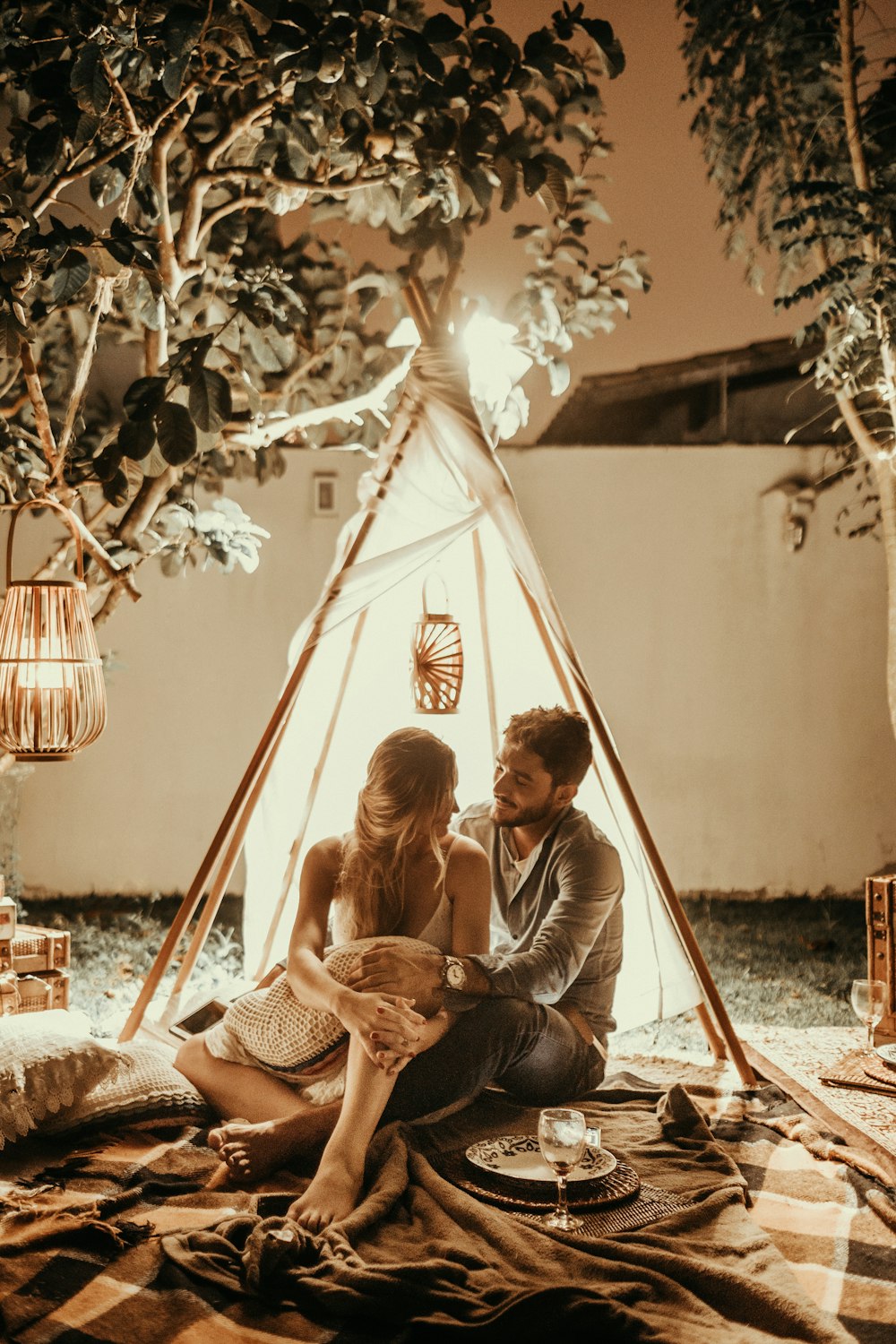 pareja sentada dentro de la cabaña del tipi con luces