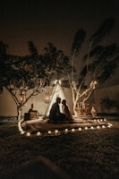 A cozy outdoor wedding setup under a cream-colored stretch tent with fairy lights at dusk.