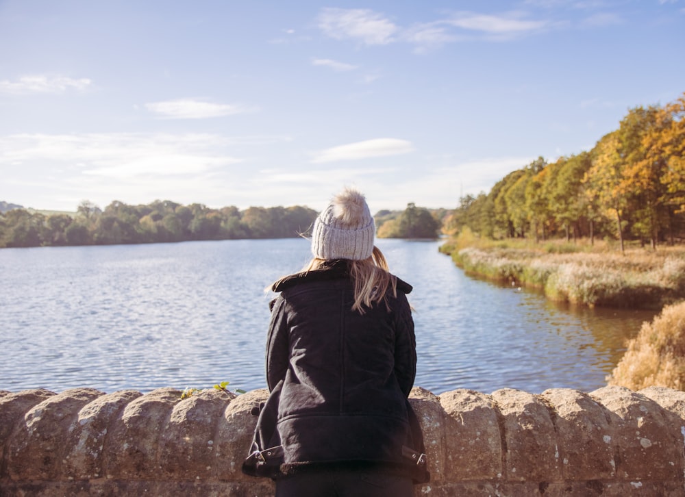 woman looking out the river while leaning on brown concrete bridge