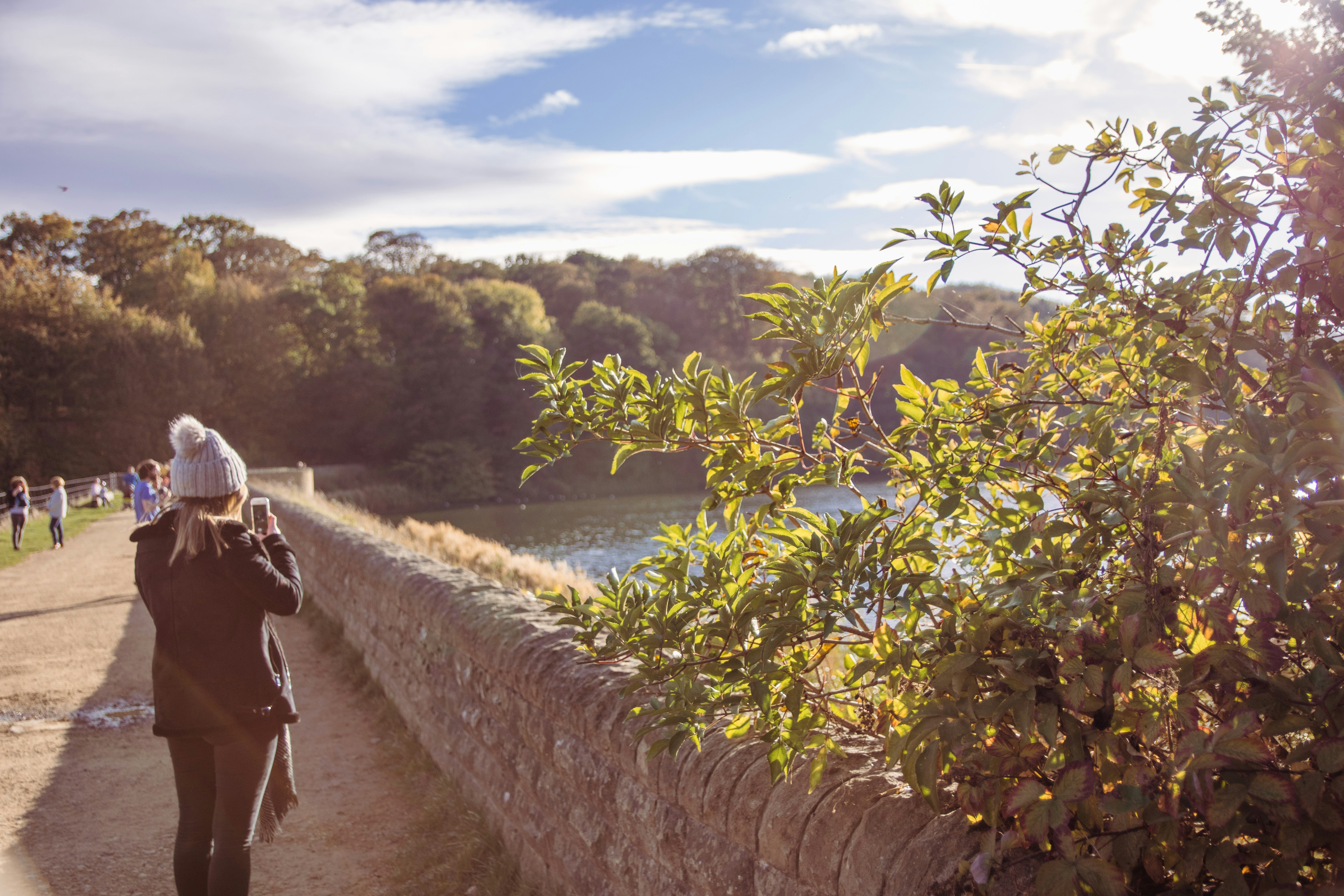 woman standing in front of concrete fence near body of water during daytime