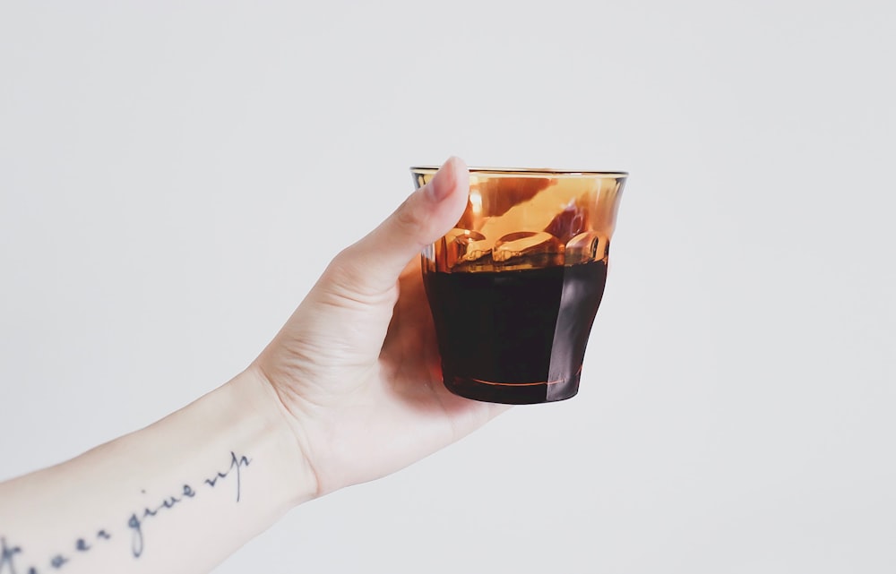 person holding almost full glass cup