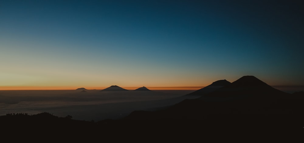 silhouette of mountains under blue and orange sky during golden hour