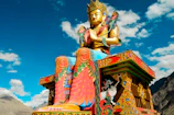 low angle photography of sitting Buddha statue under blue sky and white clouds at daytime