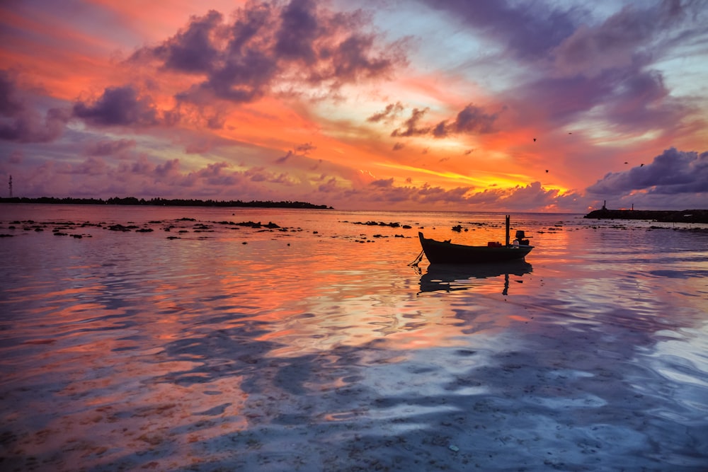 silhouette of boat on body of water during golden hour