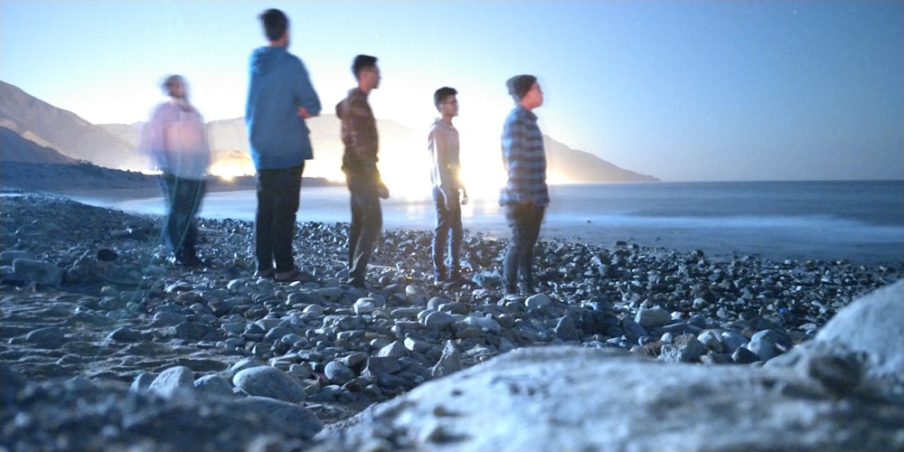 five men standing on rocky shore