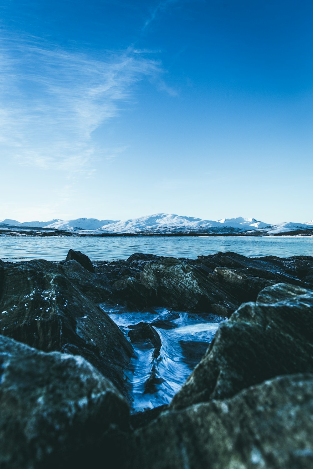 rocks near body of water under blue sky during daytime