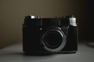 A sleek black and gold vintage film camera casting a warm spotlight glow.