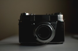 A sleek film camera set against a dark background with soft glowing lights.