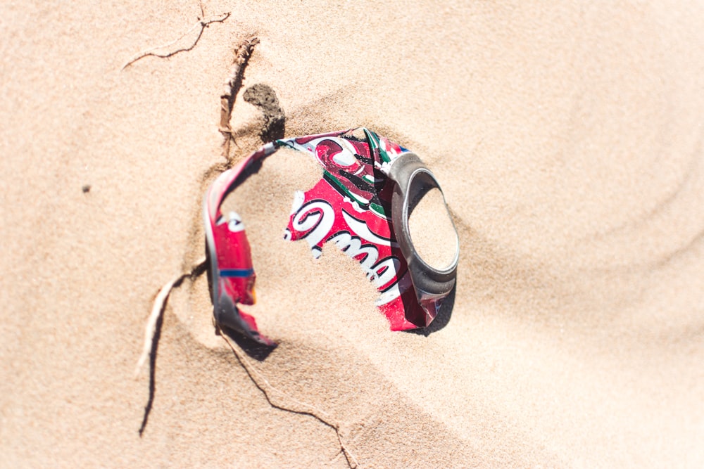 crushed red Coke can on sand