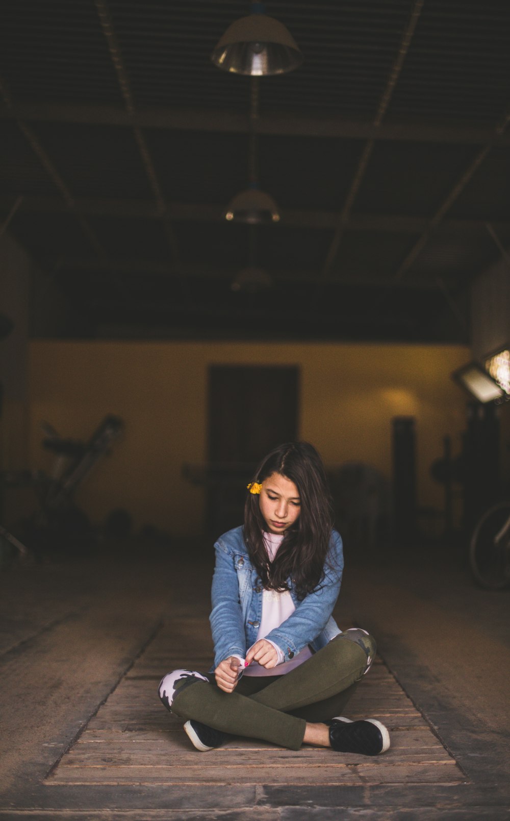 girl sitting on brown floor under unlighted lamps